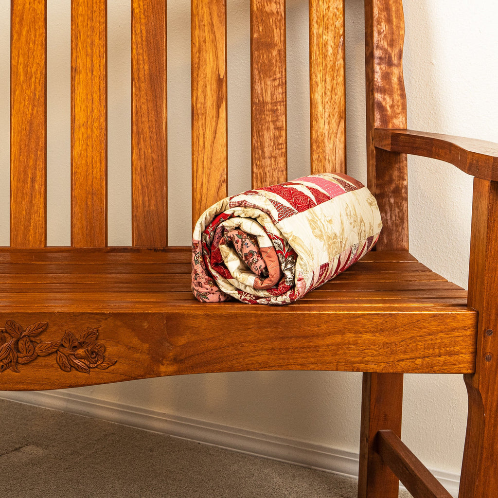 Rolled up quilt on a wooden bench.