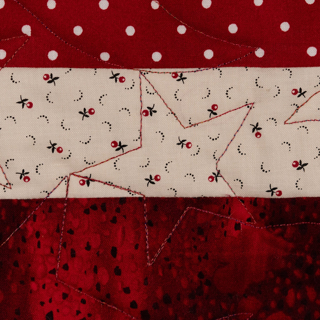 Close-up of a quilt with red, white, and black patterns