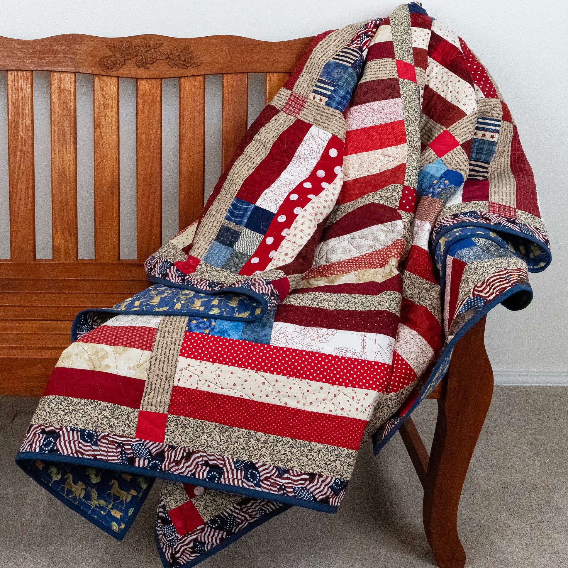 Patchwork quilt with American flag design draped over a wooden chair.