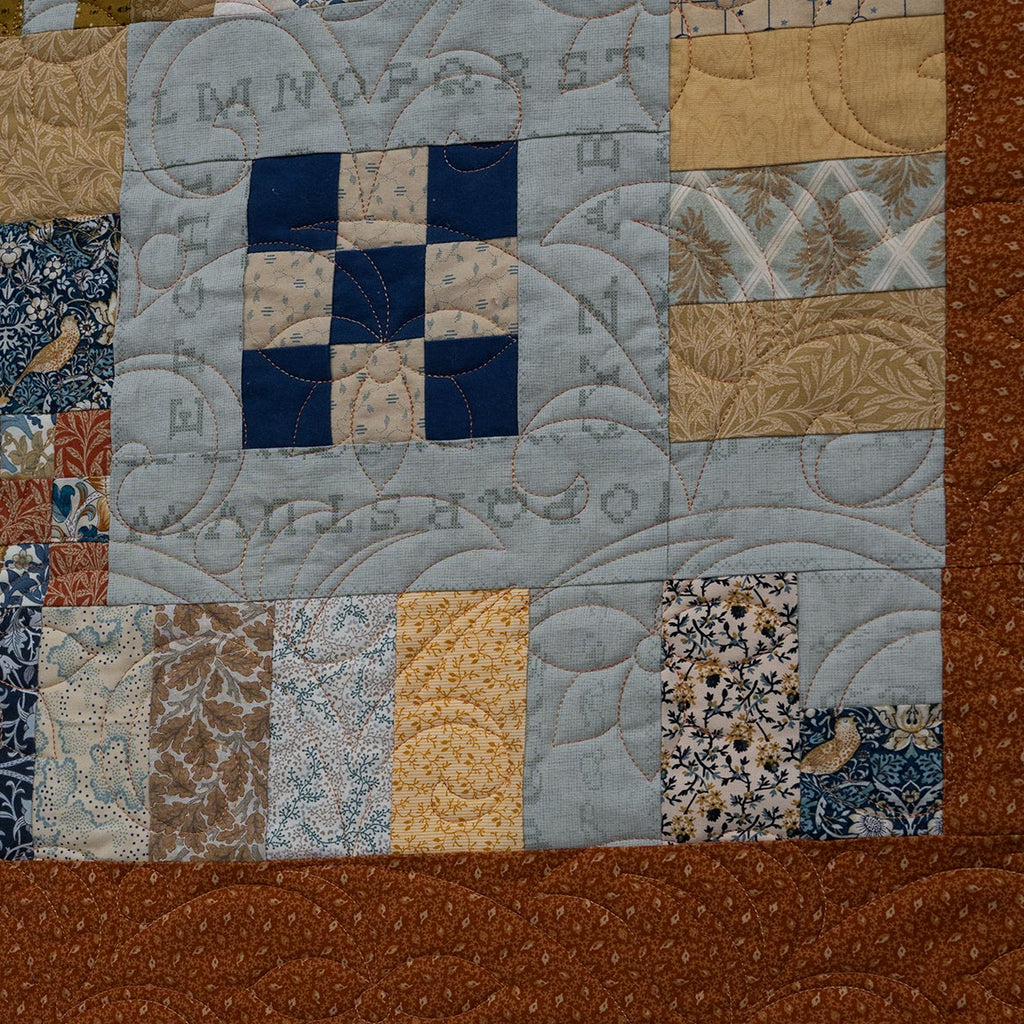 Patchwork quilt with brown border and embroidered text