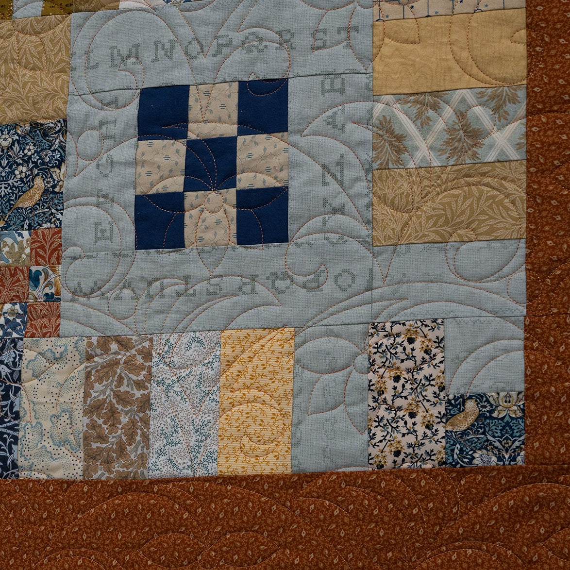 Patchwork quilt with brown border and embroidered text