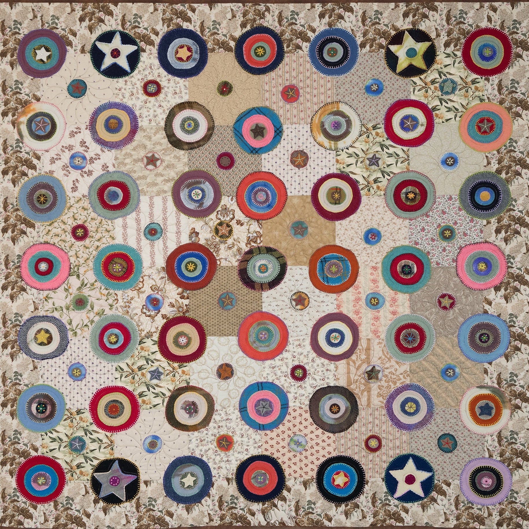 Colorful quilt with circular patterns and star designs on a beige background