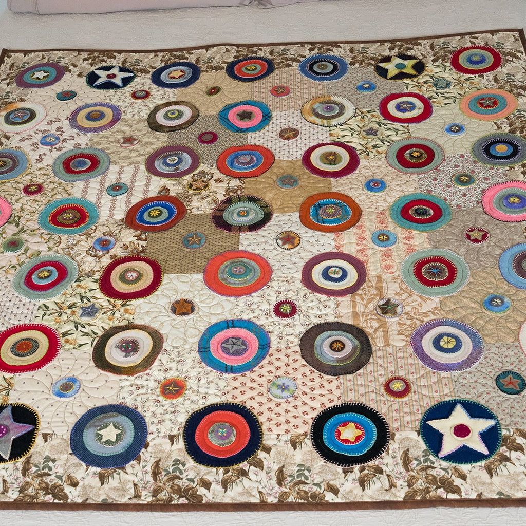 Colorful circular patterned quilt on a bed with pillows