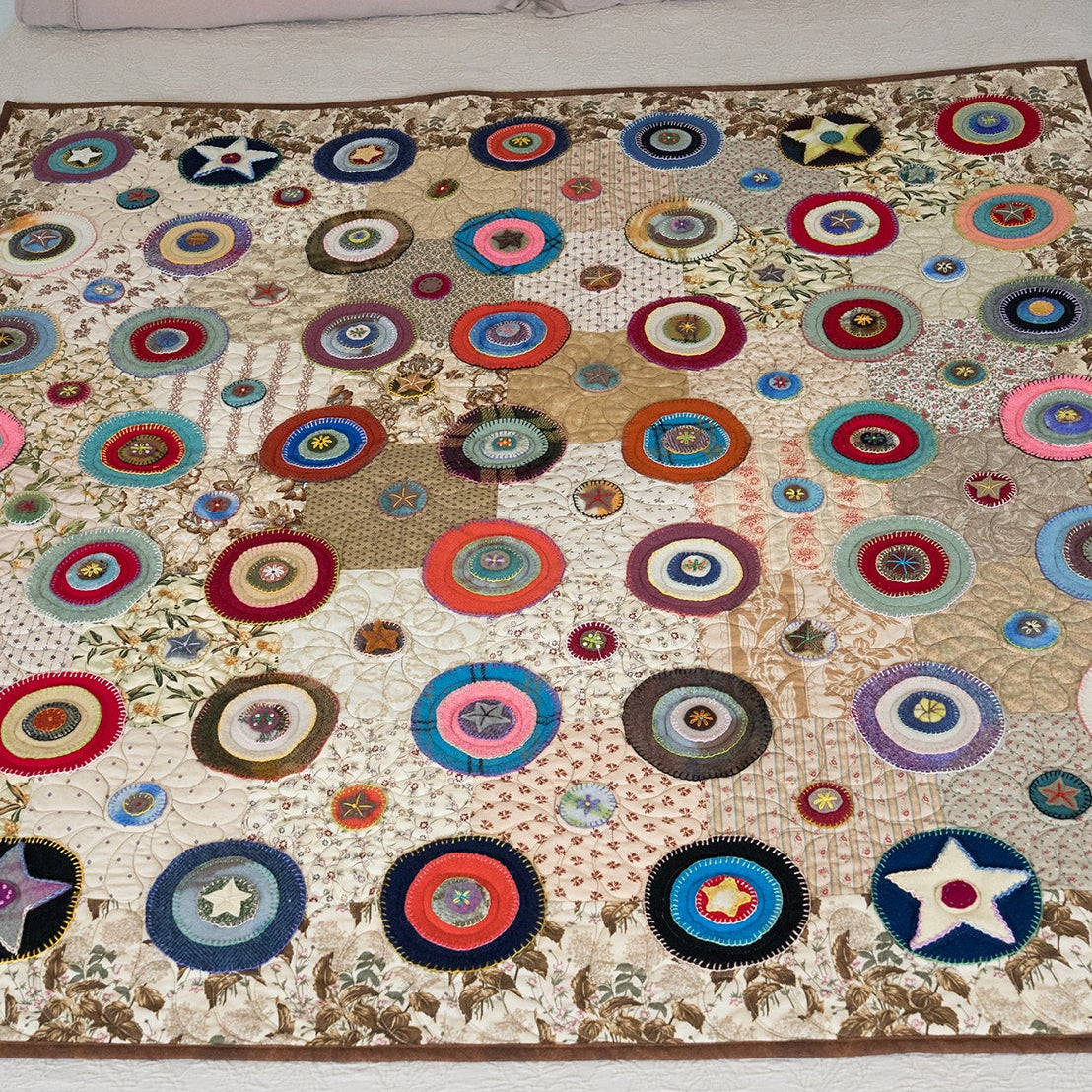 Colorful circular patterned quilt on a bed with pillows