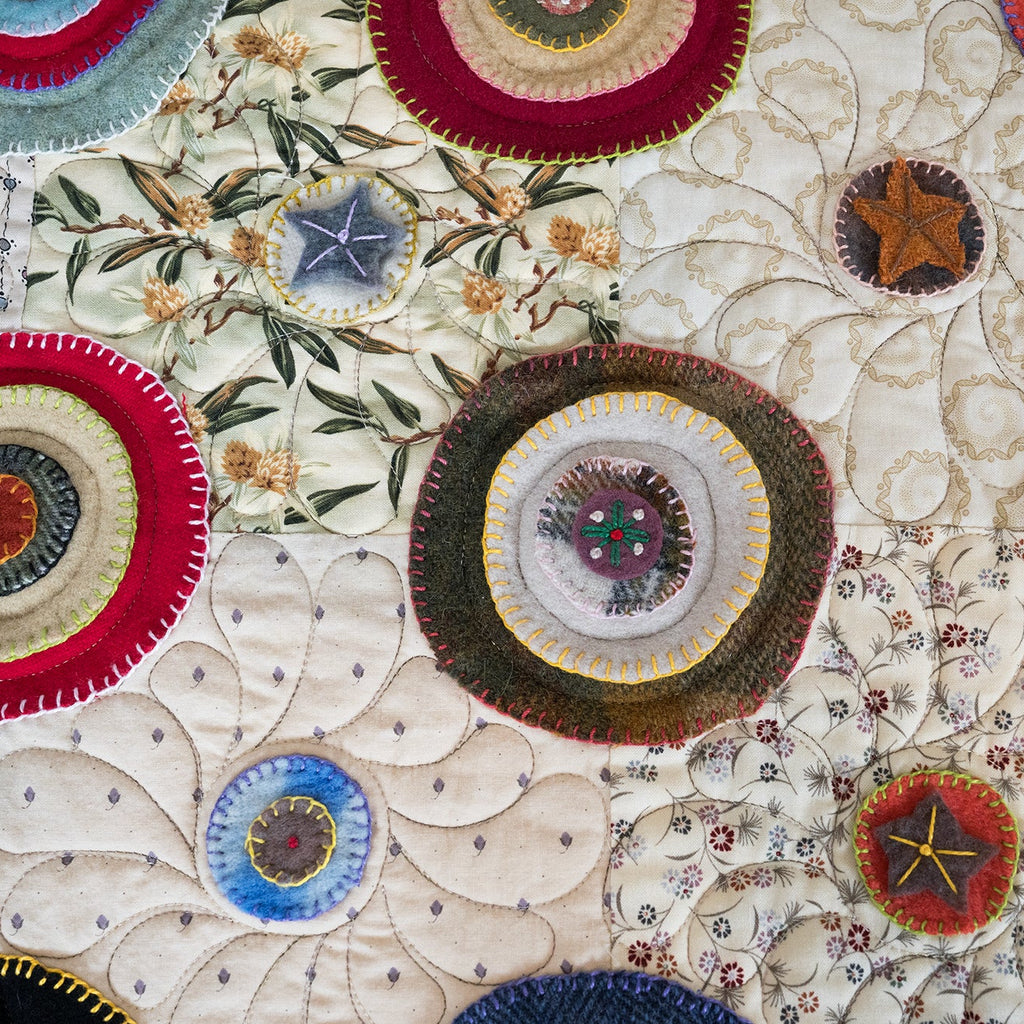 Close-up of a quilt with circular fabric pieces and floral patterns