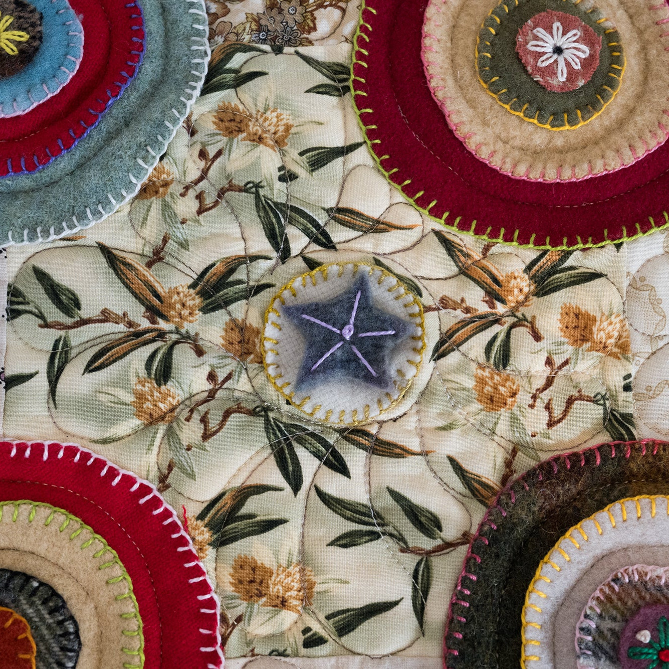Close-up of colorful embroidered fabric pieces on a floral-patterned fabric background