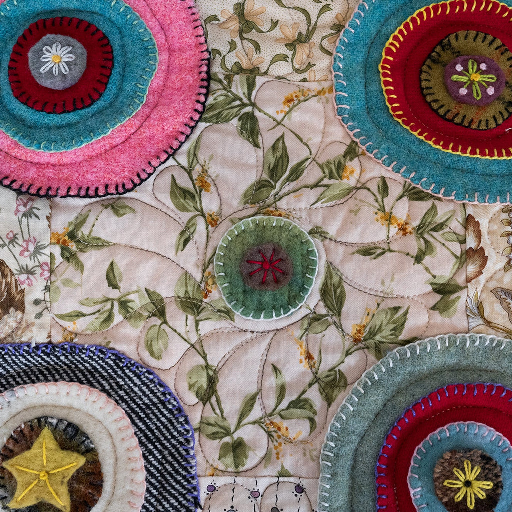 Decorative fabric with embroidered circular patterns in various colors on a floral background