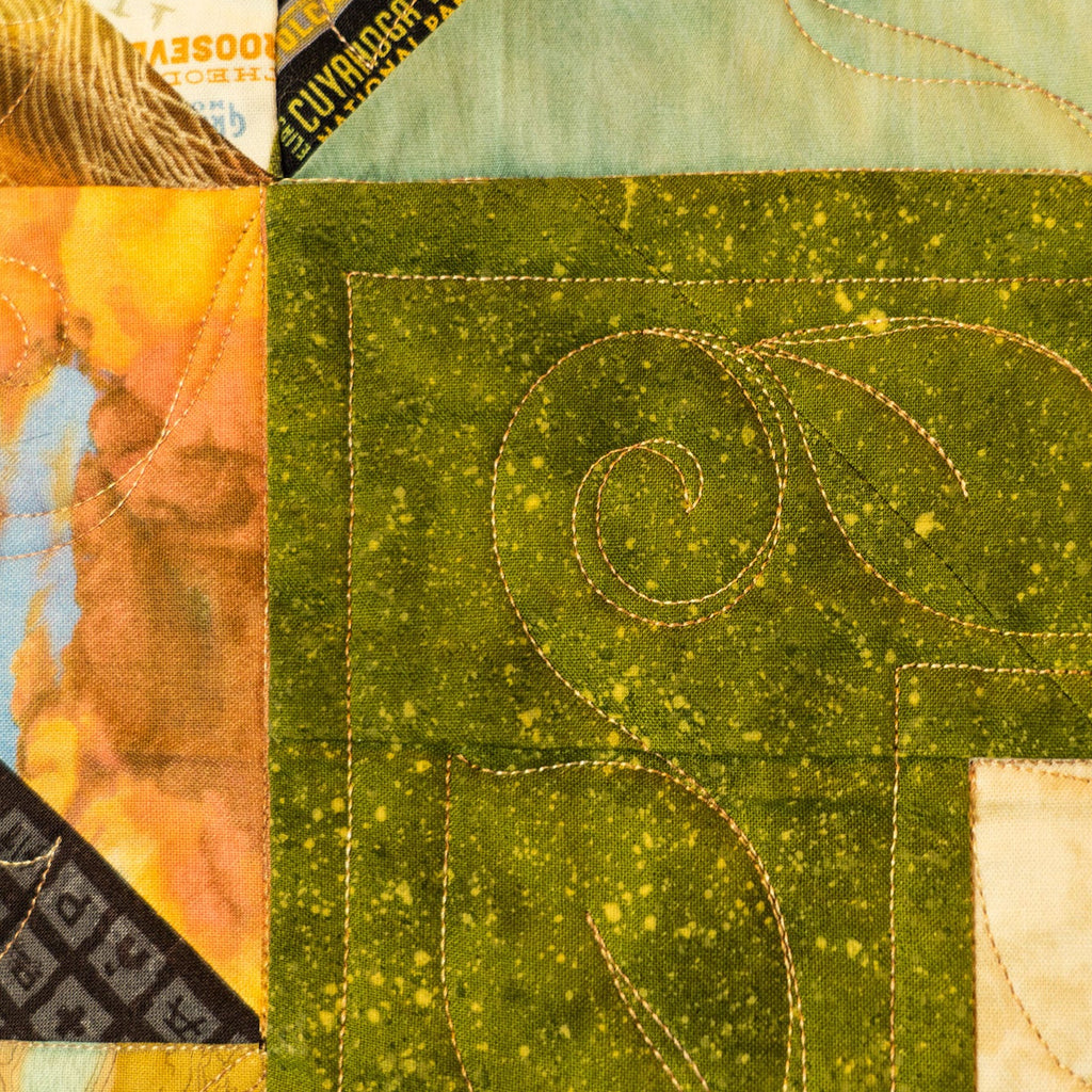 Close-up of a quilt with green fabric featuring intricate stitching patterns.