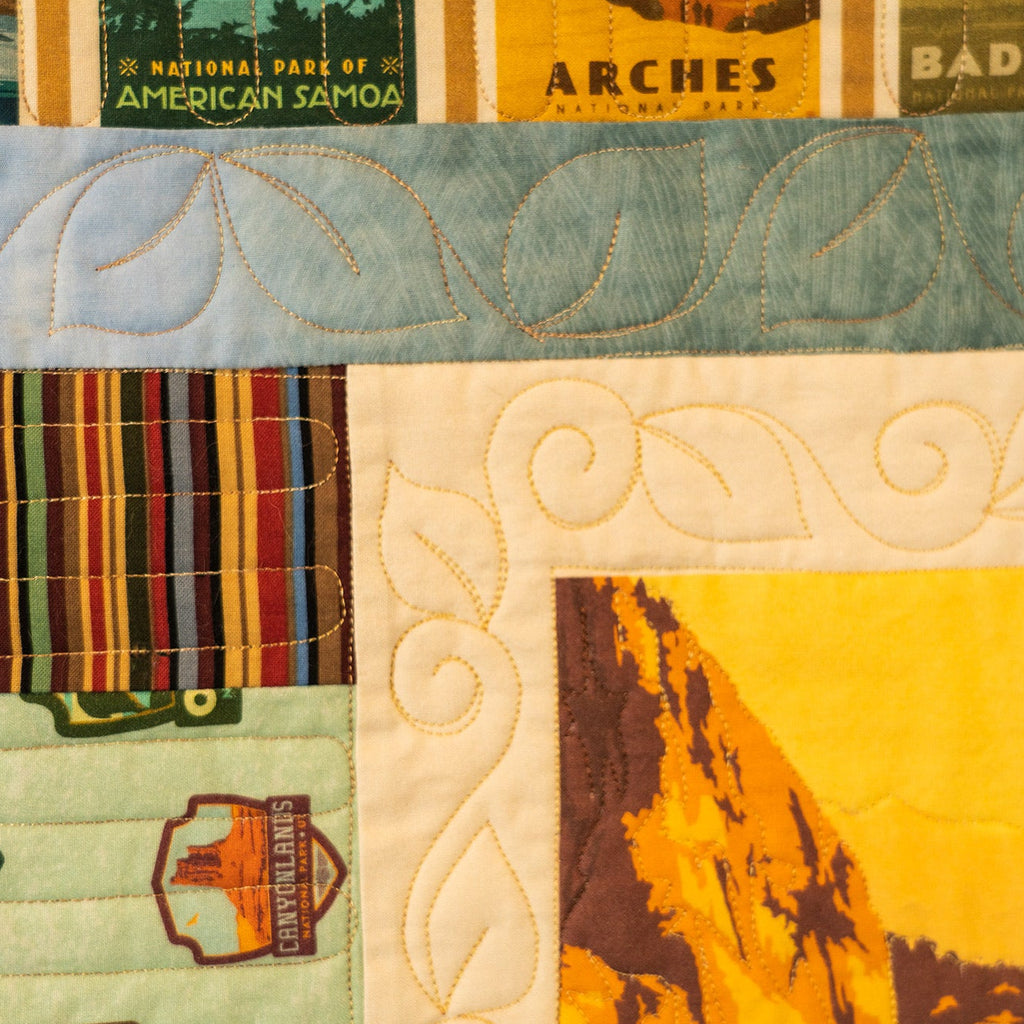 Quilt with various patterns and colors including stripes, text, and nature scenes.
